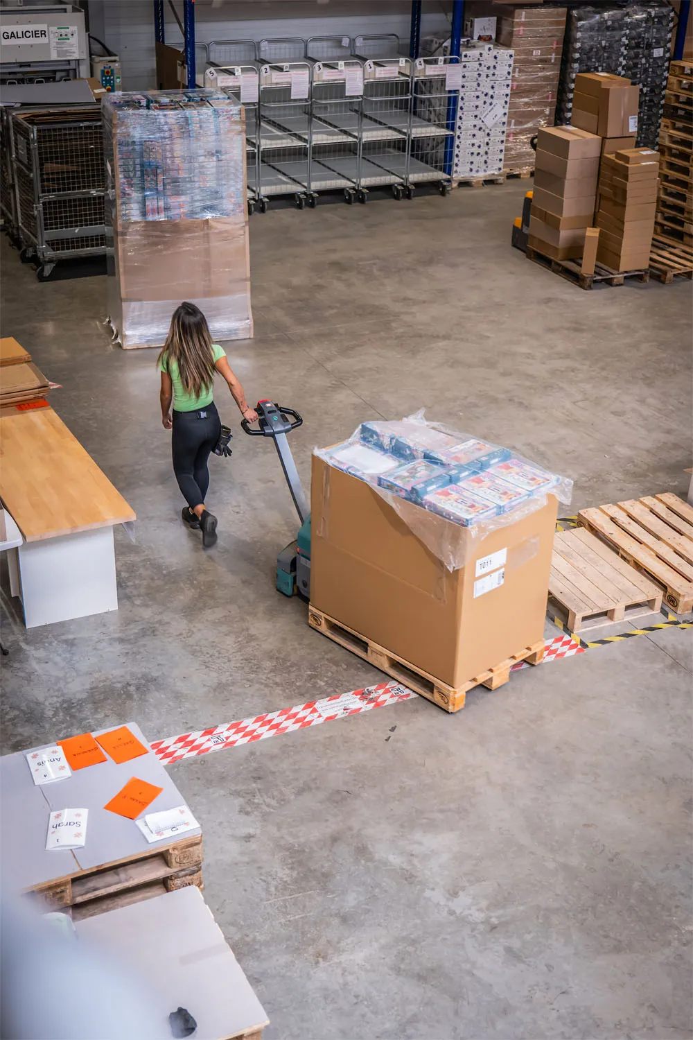 Employée au travail déplaçant un chariot de palettes